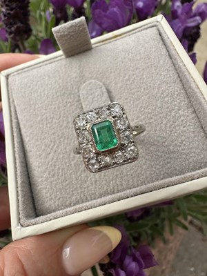 Lot 1051 - An emerald and diamond cluster ring, centred...