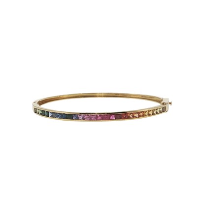 Lot 1059 - A channel-set rainbow sapphire hinged bangle...